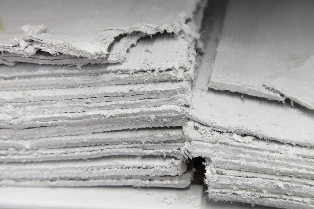 Close-up of stacked degraded asbestos cement sheets removed from a Surrey property awaiting licensed disposal